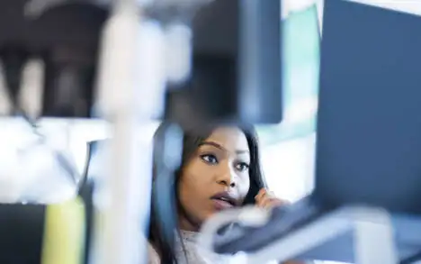 Serious businesswoman talking on telephone. Young professional is working at desk. She is in office.